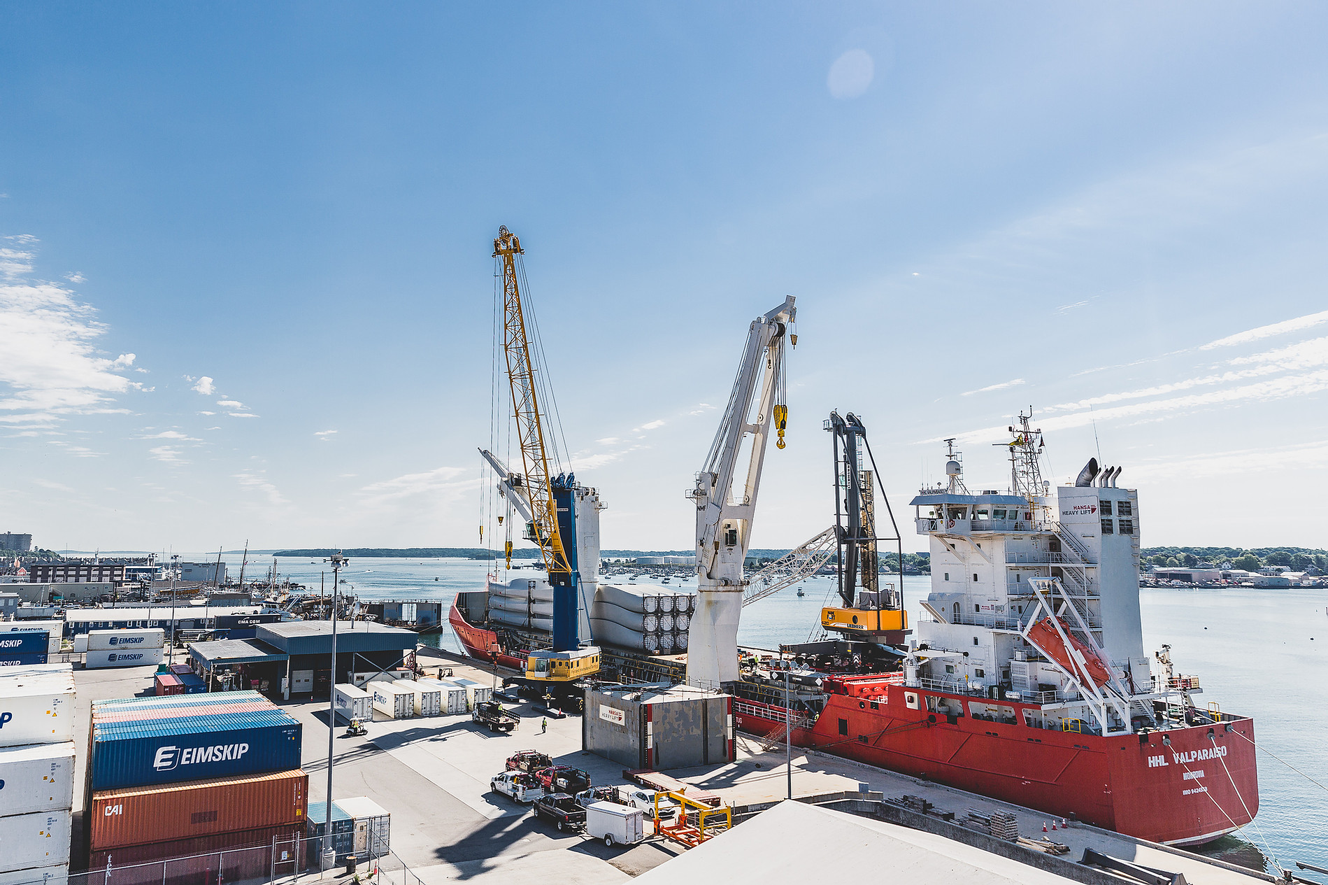 A cargo ship unloading wind turbine blades at a dock